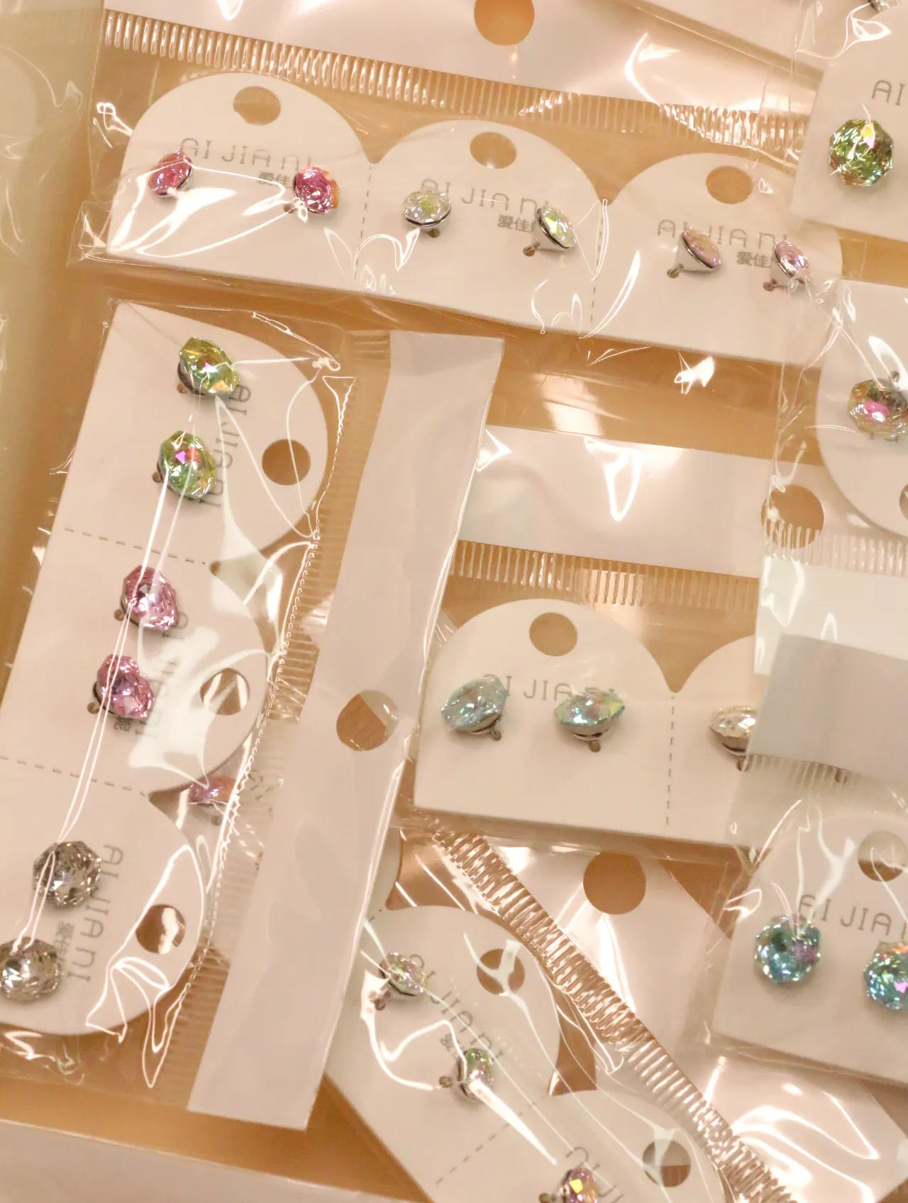 Pendientes facetados de colores surtidos en envoltorios transparentes — lote de pendientes dorados, primer plano · Lotes Bisutería (0015)