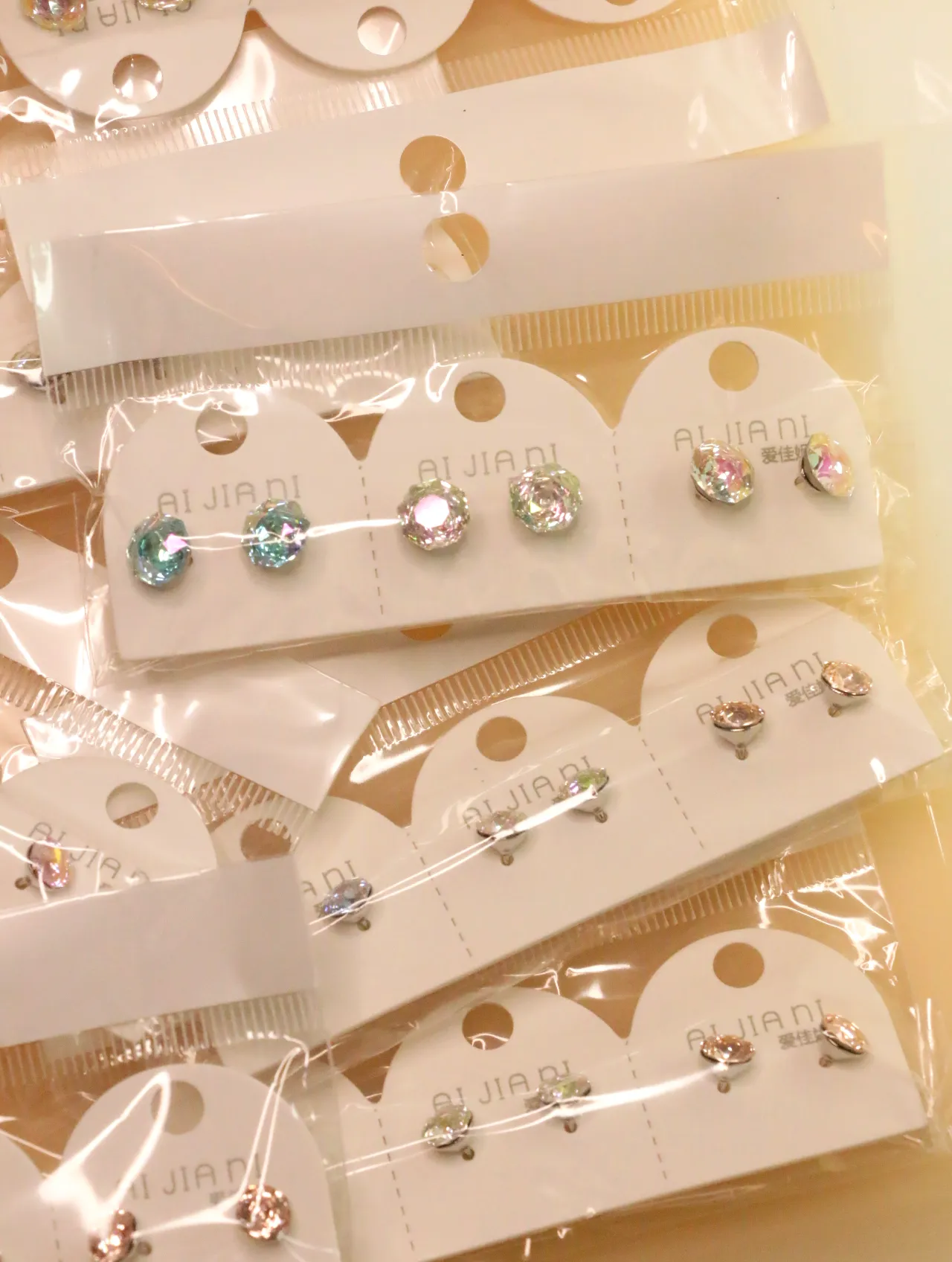 Soportes expositores con pendientes brillantes en tonos pastel — lote de pendientes originales, detalle del acabado · Lotes Bisutería (0015)