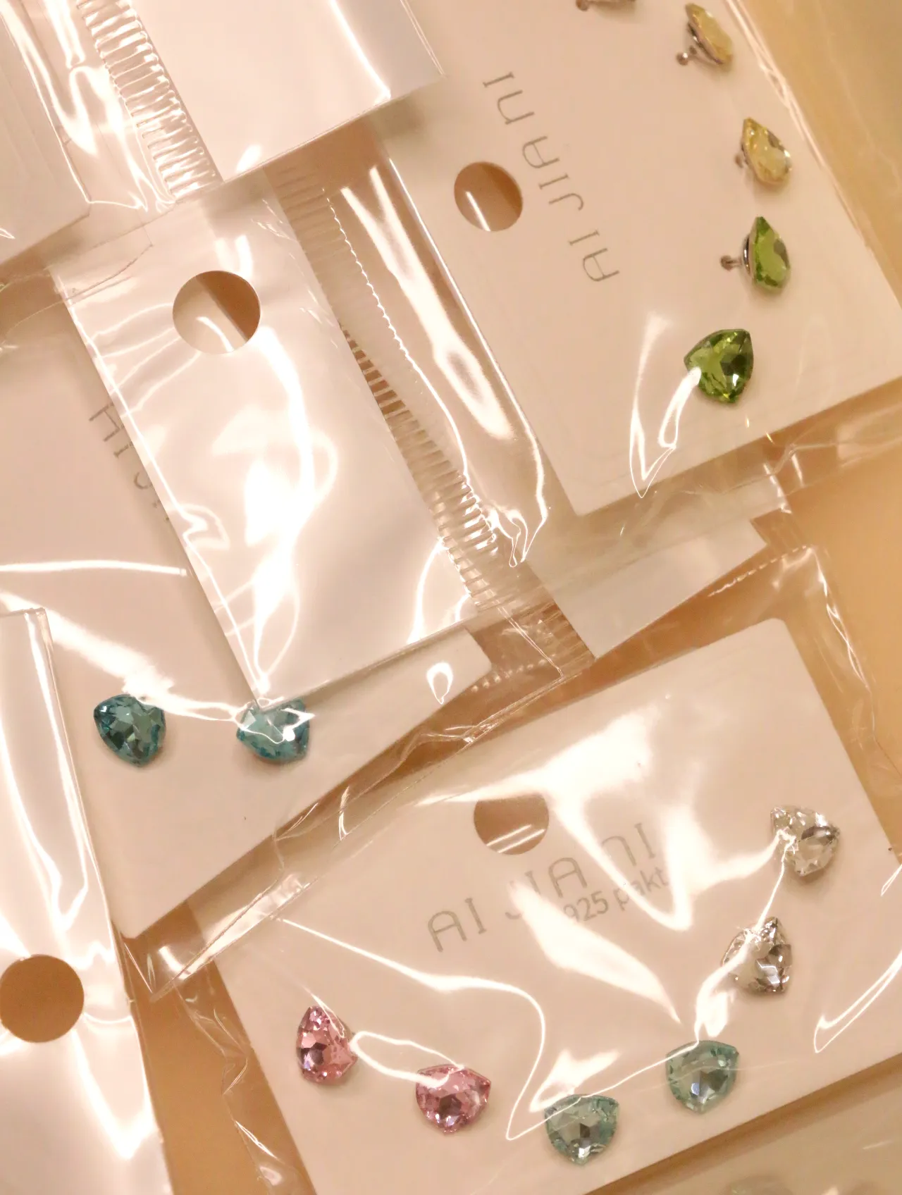 Pendientes facetados de colores en envoltorios transparentes — lote de pendientes dorados, primer plano · Lotes Bisutería (0018)