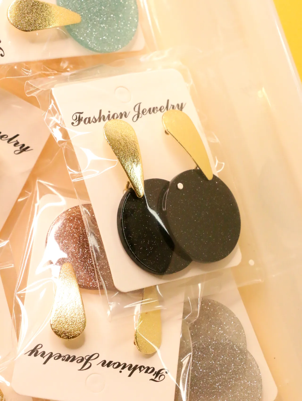 Pendientes largos de discos negros con detalles dorados sobre tarjeta — lote de pendientes de moda, vista lateral · Lotes Bisutería (0020)