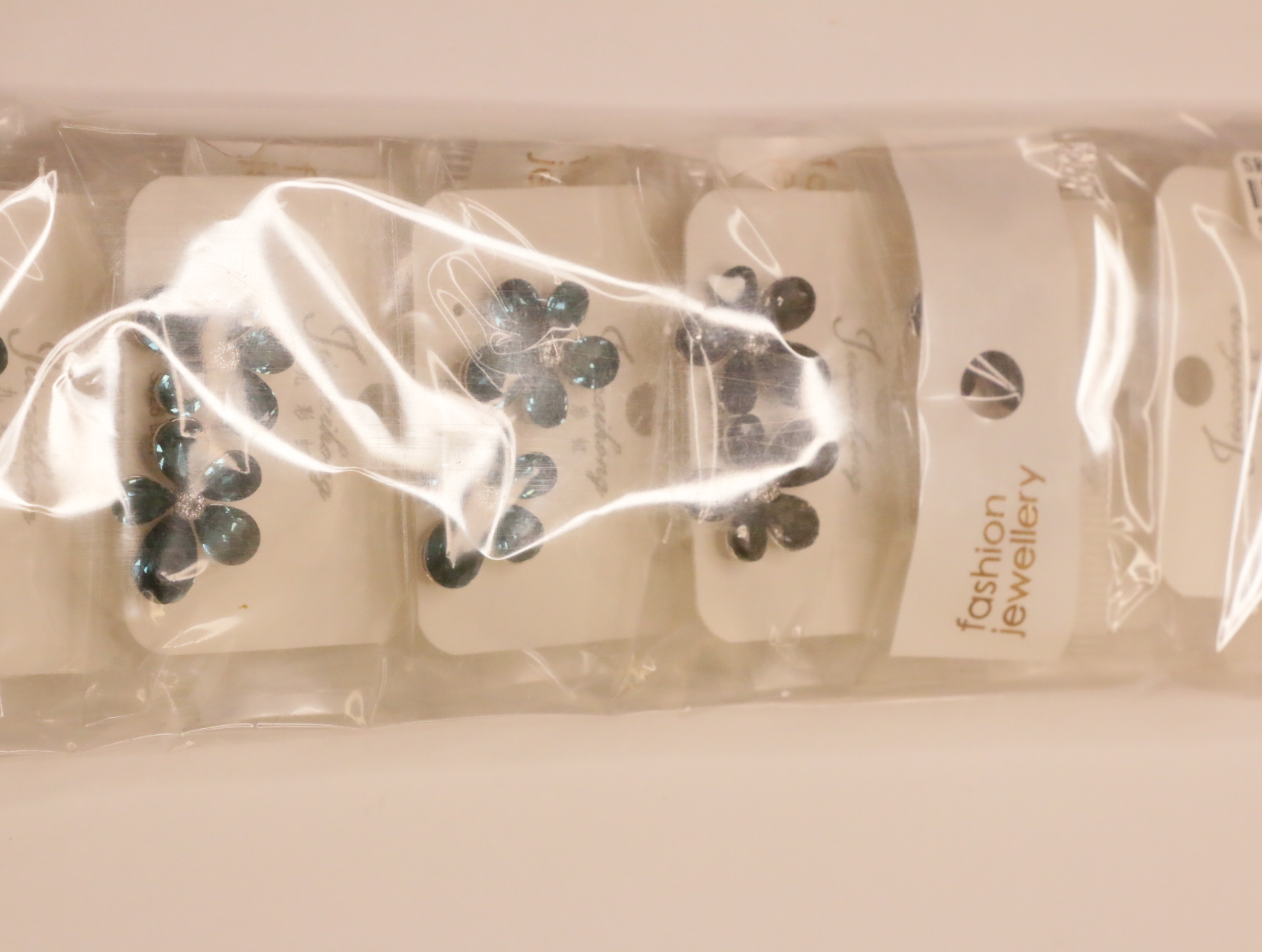 Detalle de pendientes florales en bolsas protectoras — lote de bisutería de moda, vista lateral · Lotes Bisutería (101)