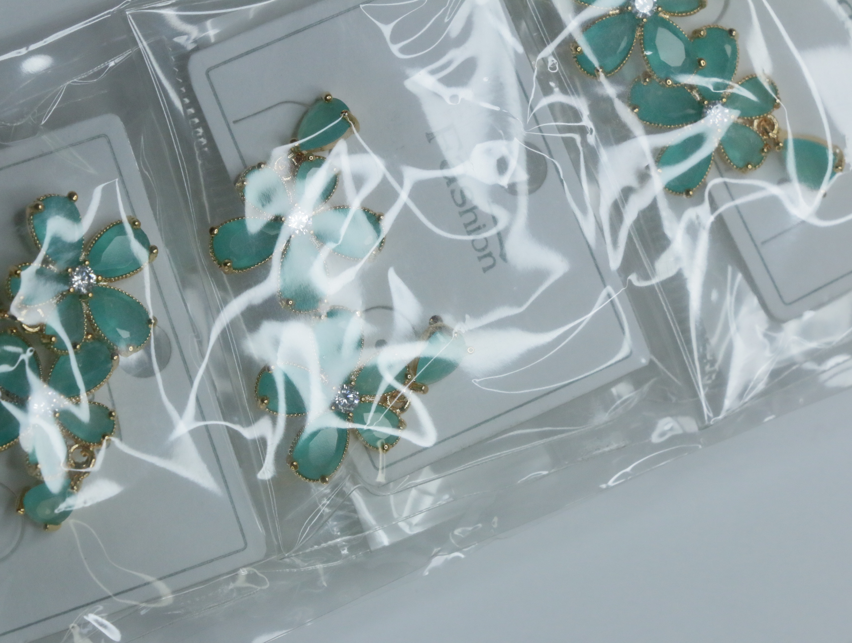 Detalle de los pendientes de flores verdes en su envoltorio — lote de bisutería de moda, vista lateral · Lotes Bisutería (115)