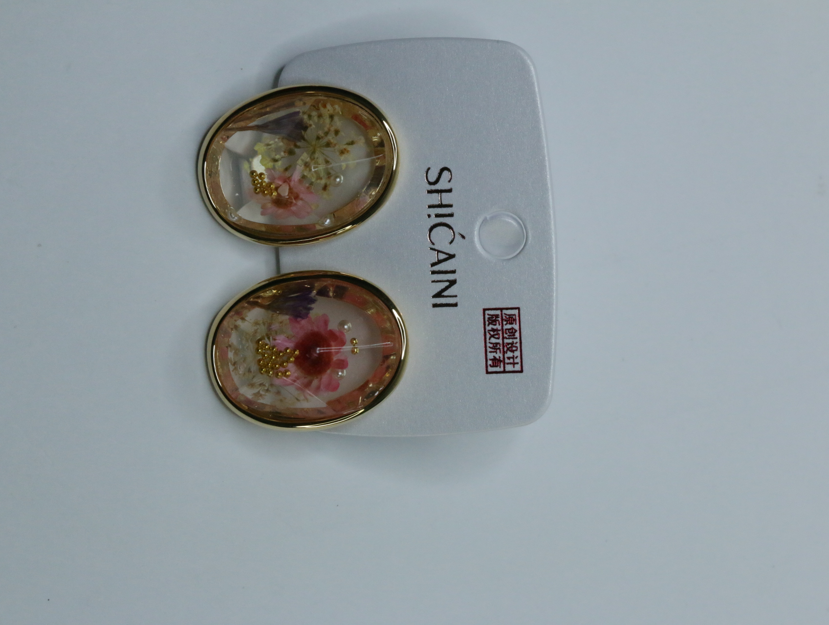 Detalle de pendientes ovalados dorados con decoración floral — lote de bisutería para mujer, vista principal · Lotes Bisutería (118)