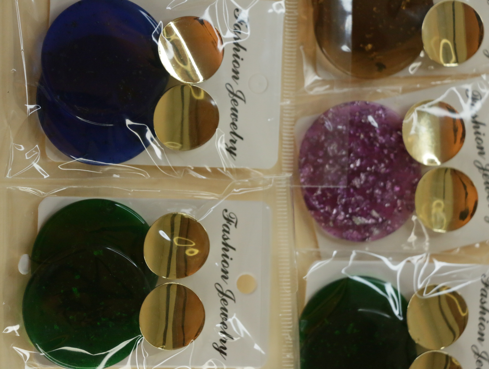 Detalle de pendientes azules y verdes con discos dorados — lote de bisutería de moda, vista lateral · Lotes Bisutería (122)