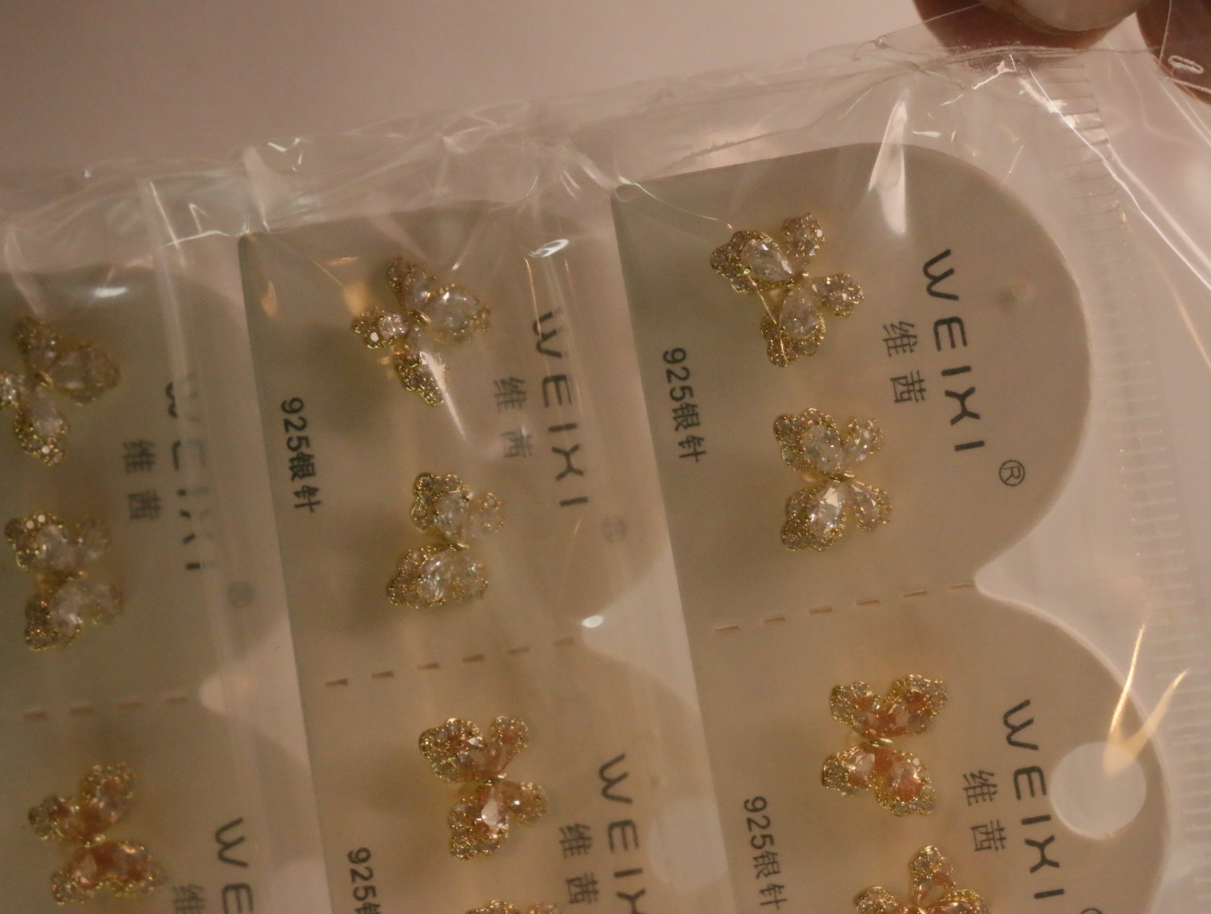 Pendientes de mariposa con piedras transparentes en su envoltorio — lote de bisutería originales, detalle del acabado · Lotes Bisutería (96)