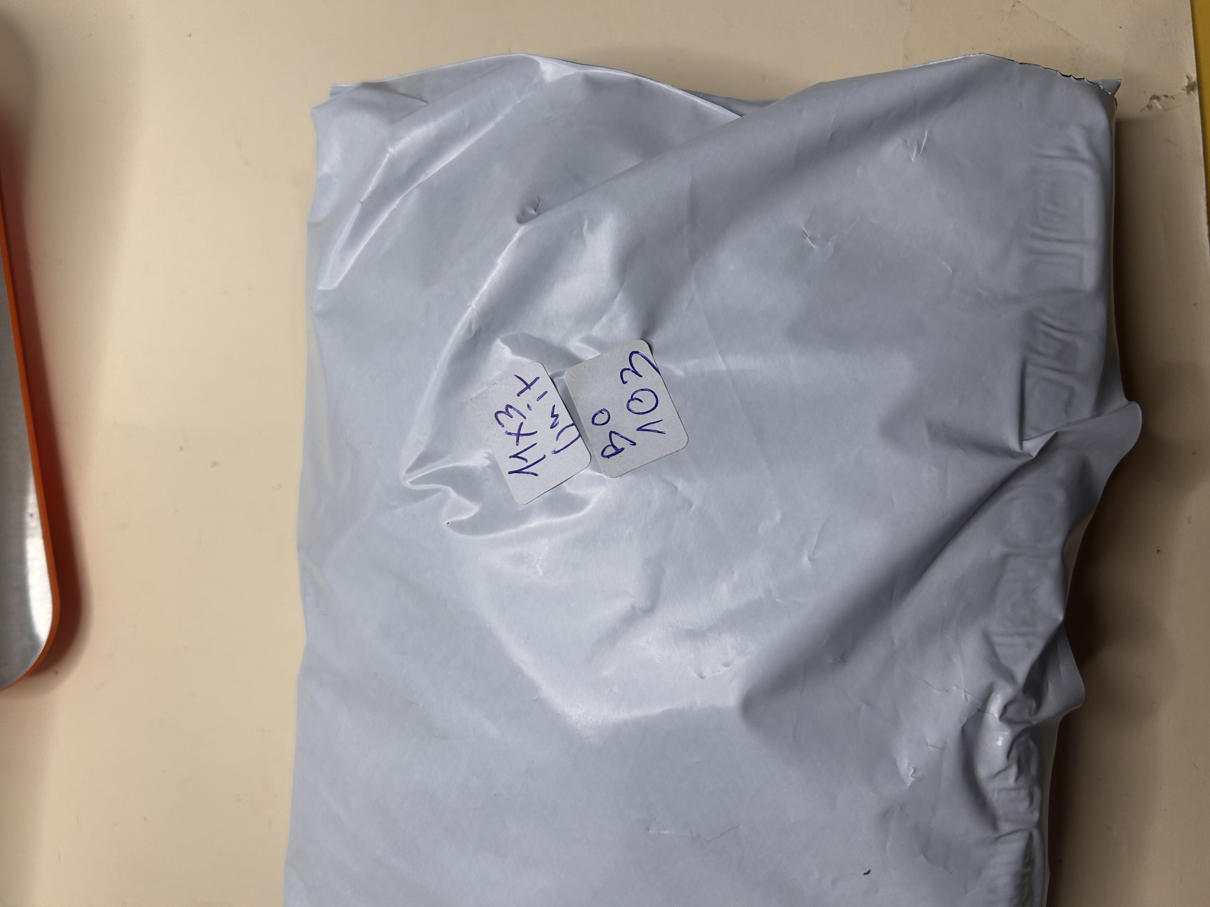 Un paquete blanco tipo bolsa de envío con dos etiquetas, una escrita a mano '11x3 Unidad' y 'BO 103'.