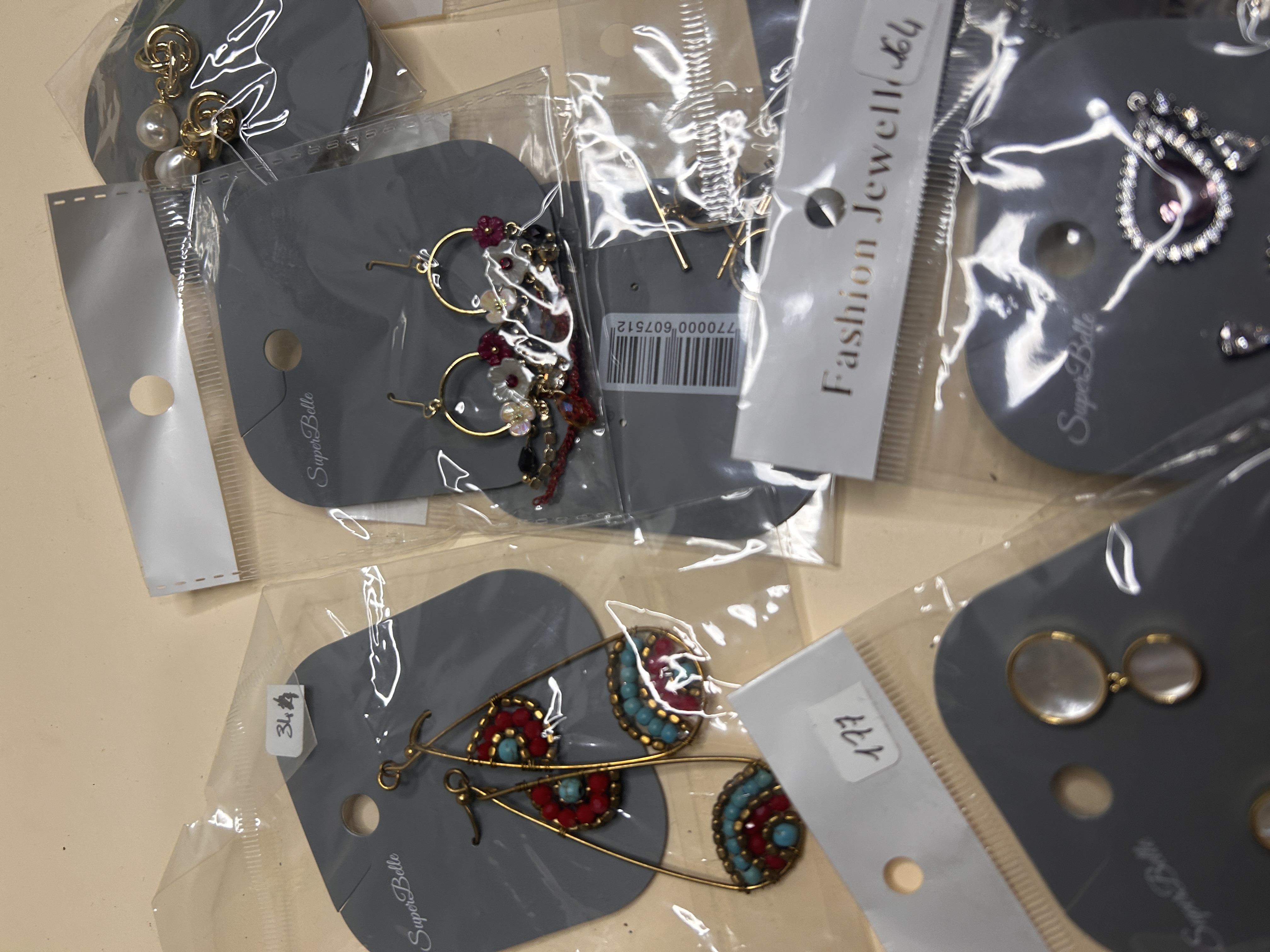 Grupo de pendientes de bisutería que incluye elaboradas lágrimas doradas con acentos turquesa y coral, pequeños aros con cuentas y studs de nácar.