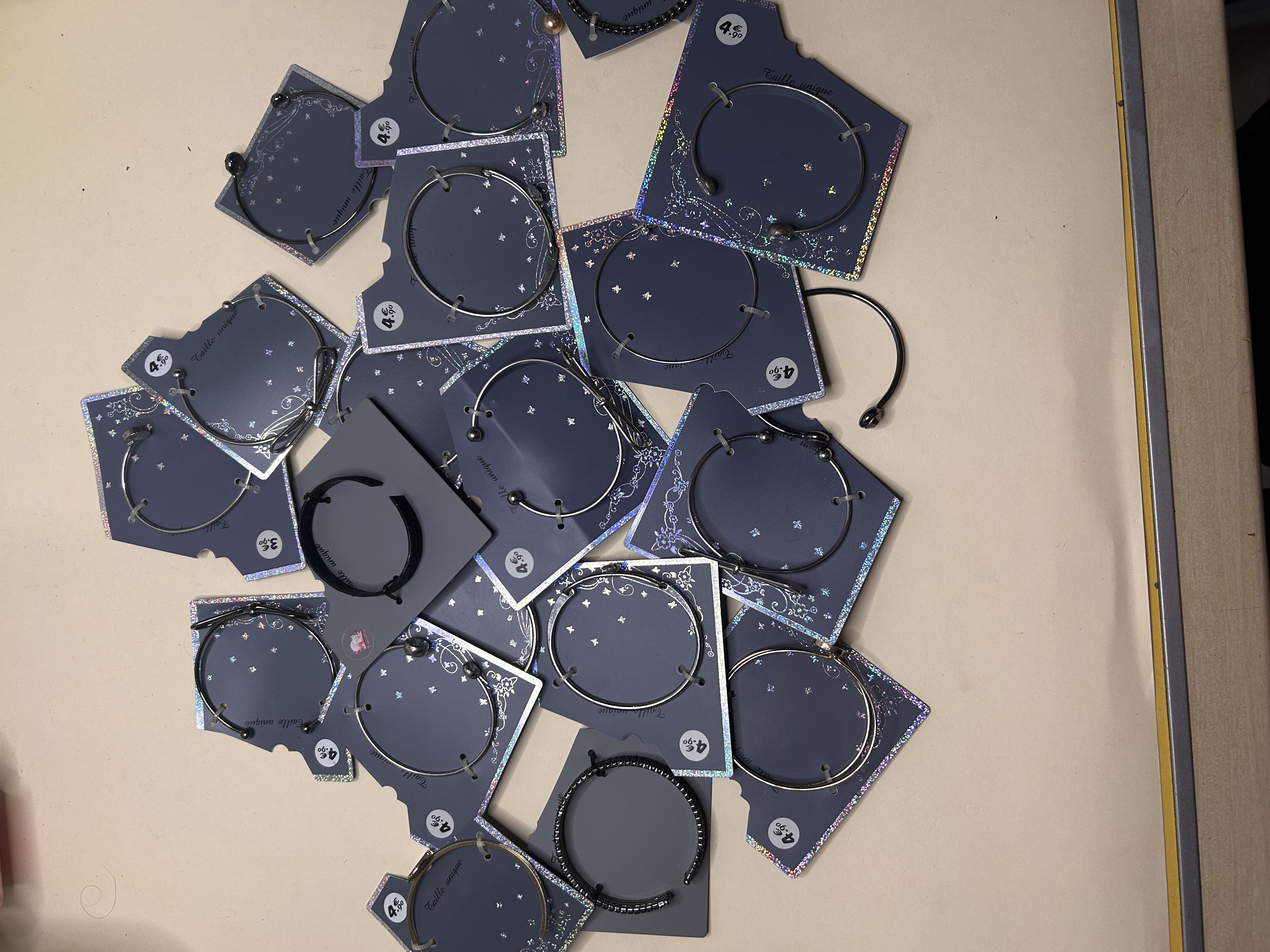 Surtido de pulseras rígidas en tarjetas expositoras sobre la mesa — lote de pendientes baratos, detalle · Lotes Bisutería (CUFFS-120)