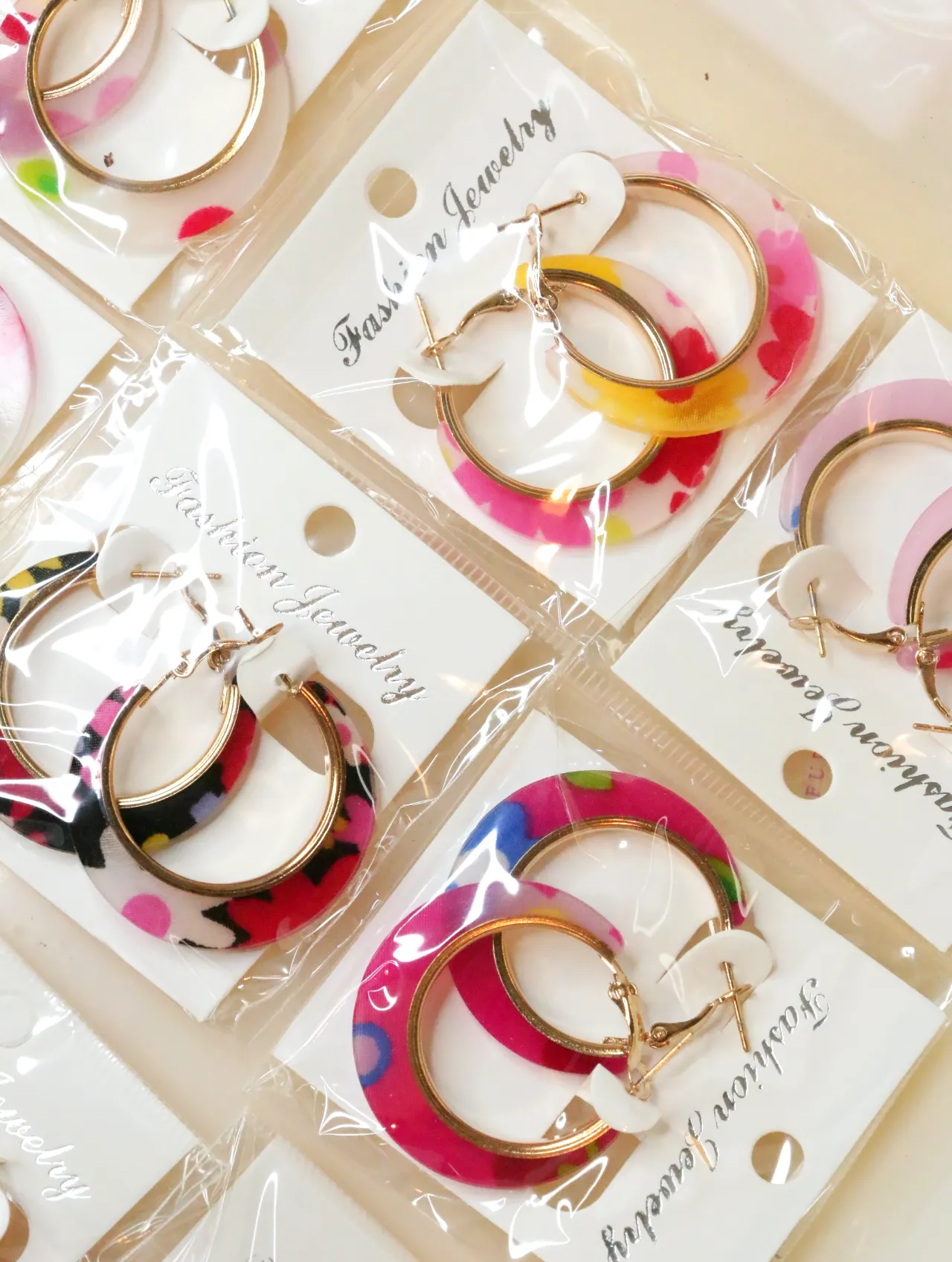 Aros florales multicolor sobre tarjetas blancas — lote de bisutería dorados, primer plano · Lotes Bisutería (H0008)