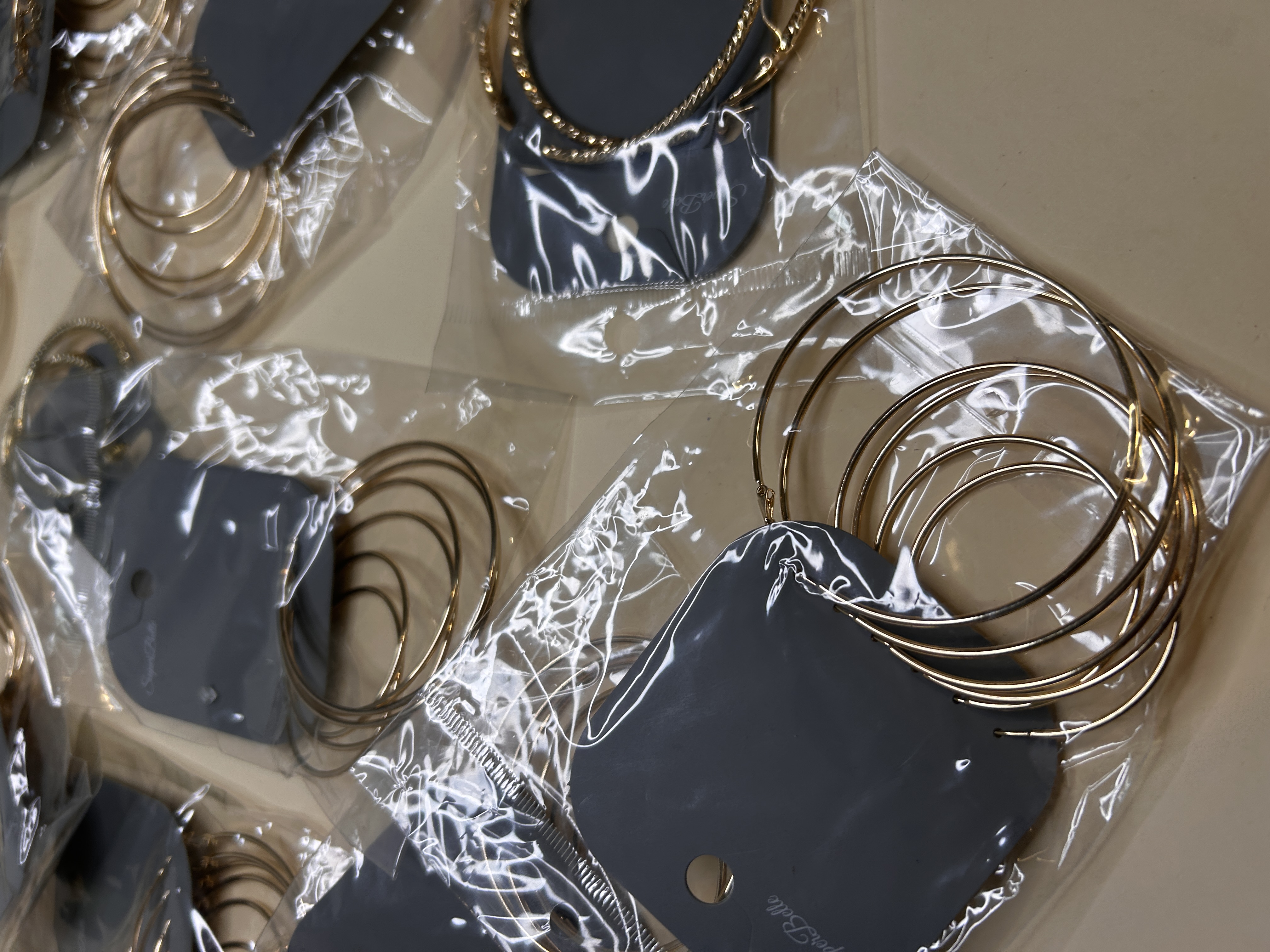 Primer plano de pendientes de aro dorados sobre tarjetas grises — lote de pendientes dorados, primer plano · Lotes Bisutería (HOOP-203)