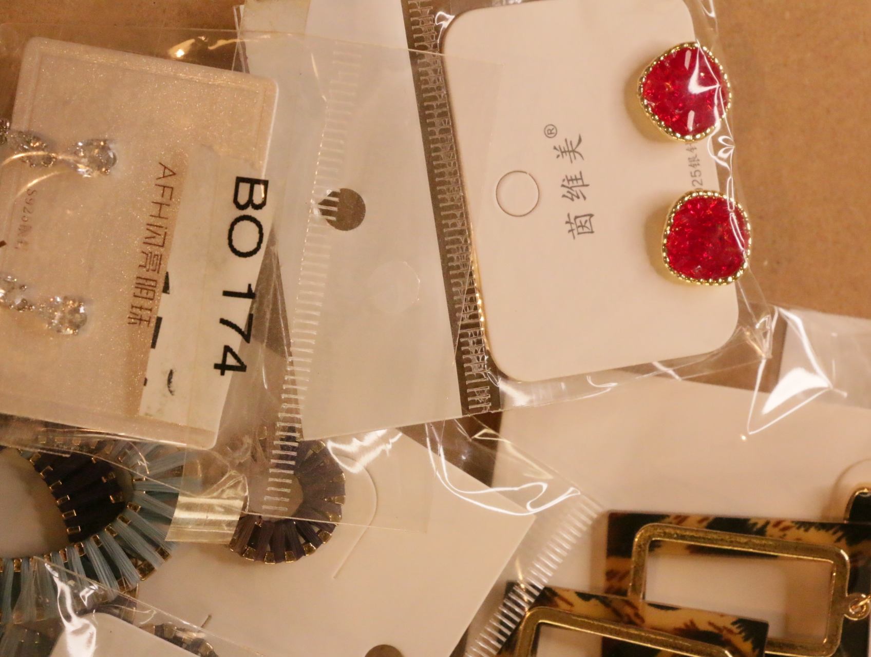 Pendientes de botón rojos junto a diseños brillantes y texturizados — lote de bisutería dorados, primer plano · Lotes Bisutería (LT039)