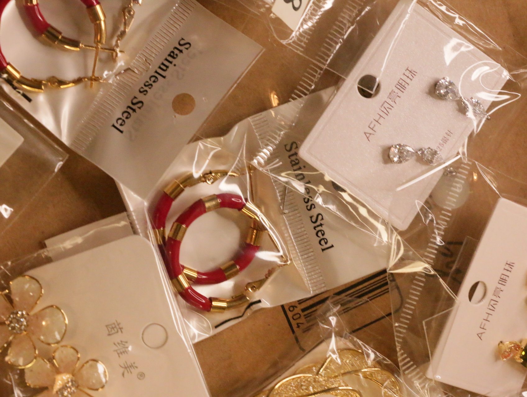 Aros rojos y dorados junto a pendientes brillantes y florales — lote de bisutería baratos, detalle · Lotes Bisutería (LT040)
