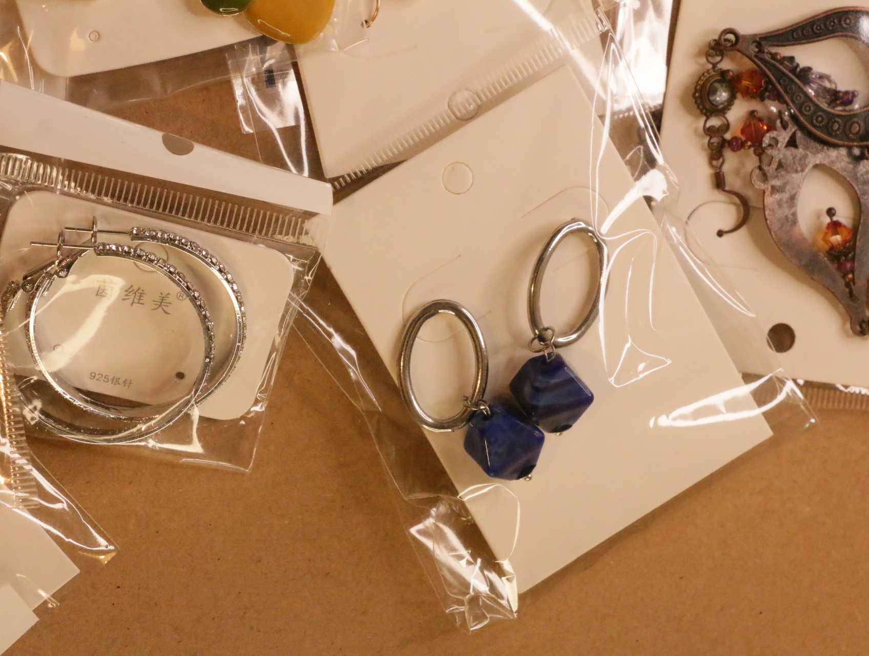 Pendientes ovalados colgantes con cuentas azules junto a aros plateados — lote de bisutería originales, detalle del acabado · Lotes Bisutería (LT041)
