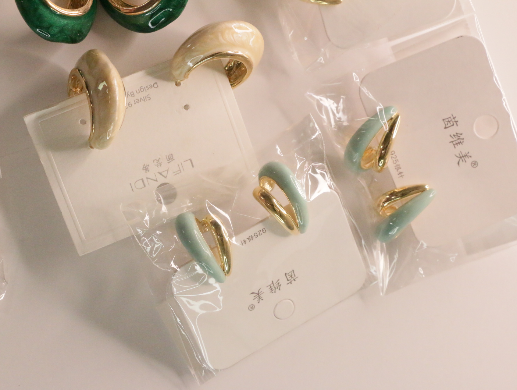 Pendientes verde menta y crema sobre sus soportes — lote de bisutería dorados, primer plano · Lotes Bisutería (LT045)