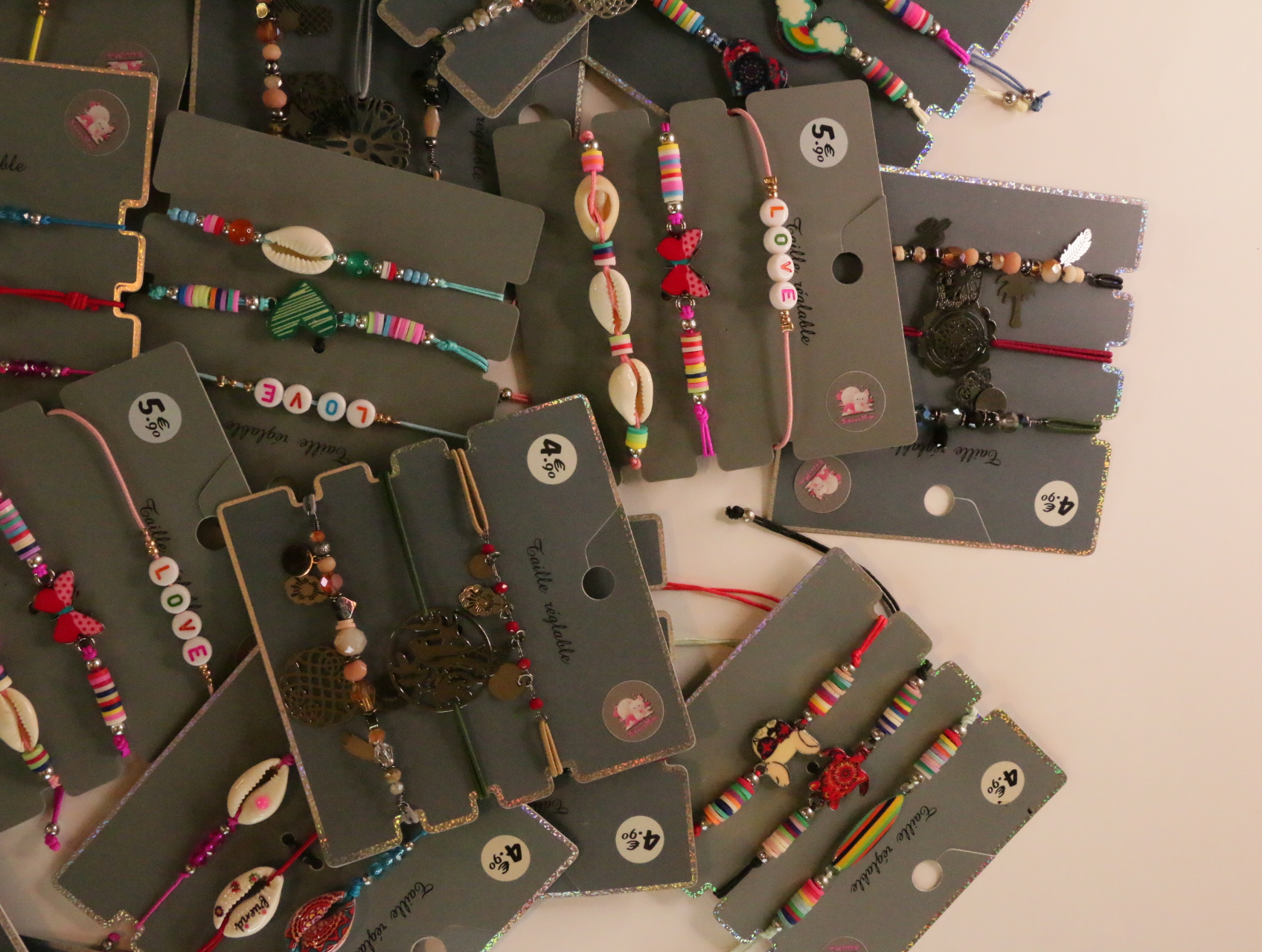 Detalle de pulseras con cuentas de letras y colgantes decorativos — lote de bisutería de moda, vista lateral · Lotes Bisutería (LT054)