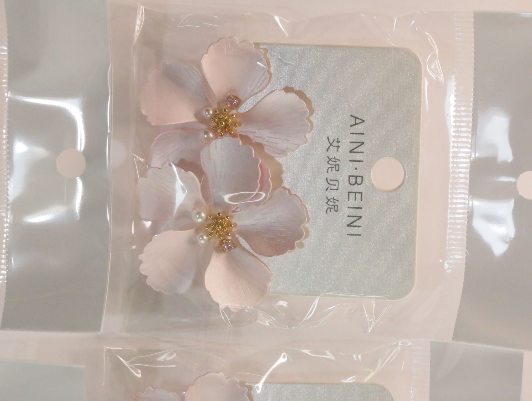 Pendientes de flores rosas con centros dorados sobre tarjeta — lote de bisutería dorados, primer plano · Lotes Bisutería (LT056)
