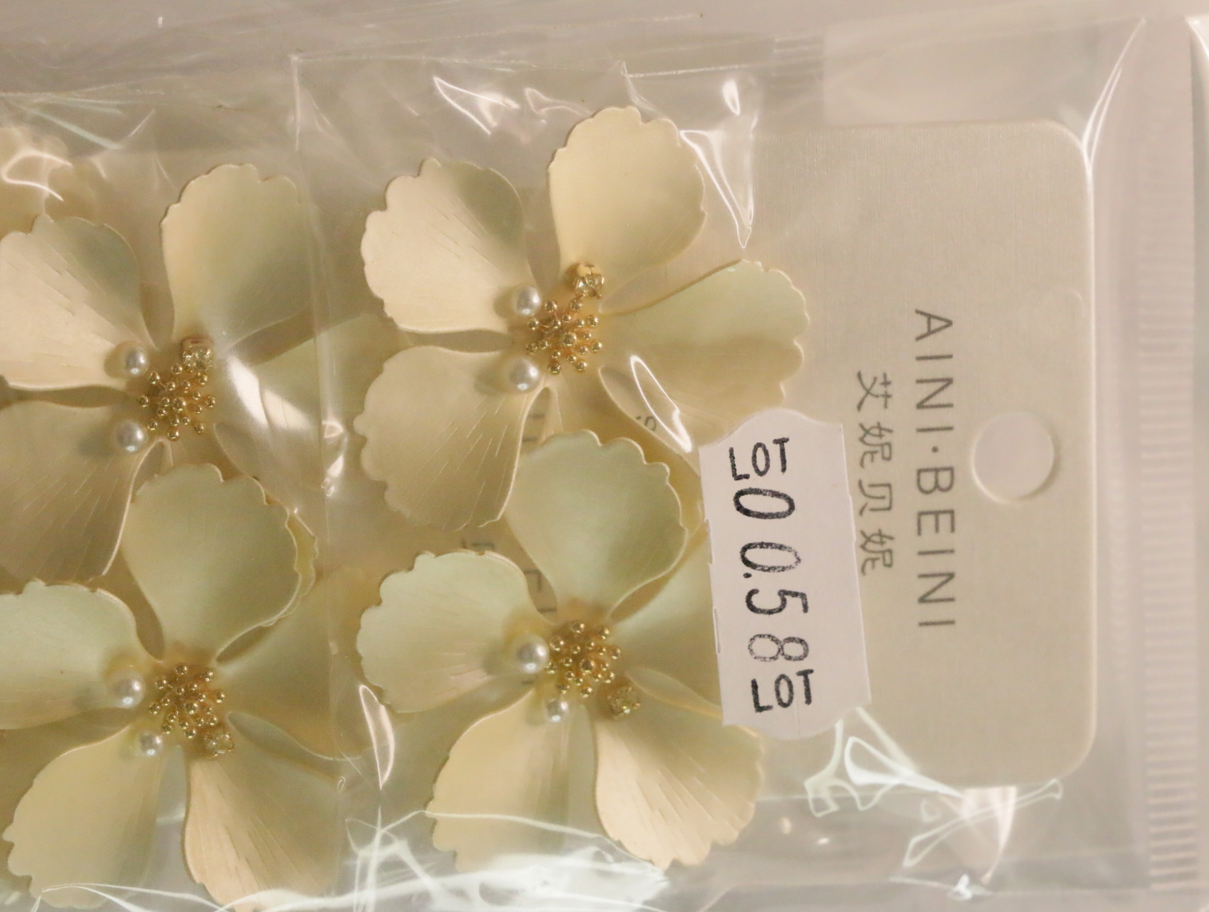 Pendientes de flores crema con etiqueta de referencia interna — lote de bisutería dorados, primer plano · Lotes Bisutería (LT058)