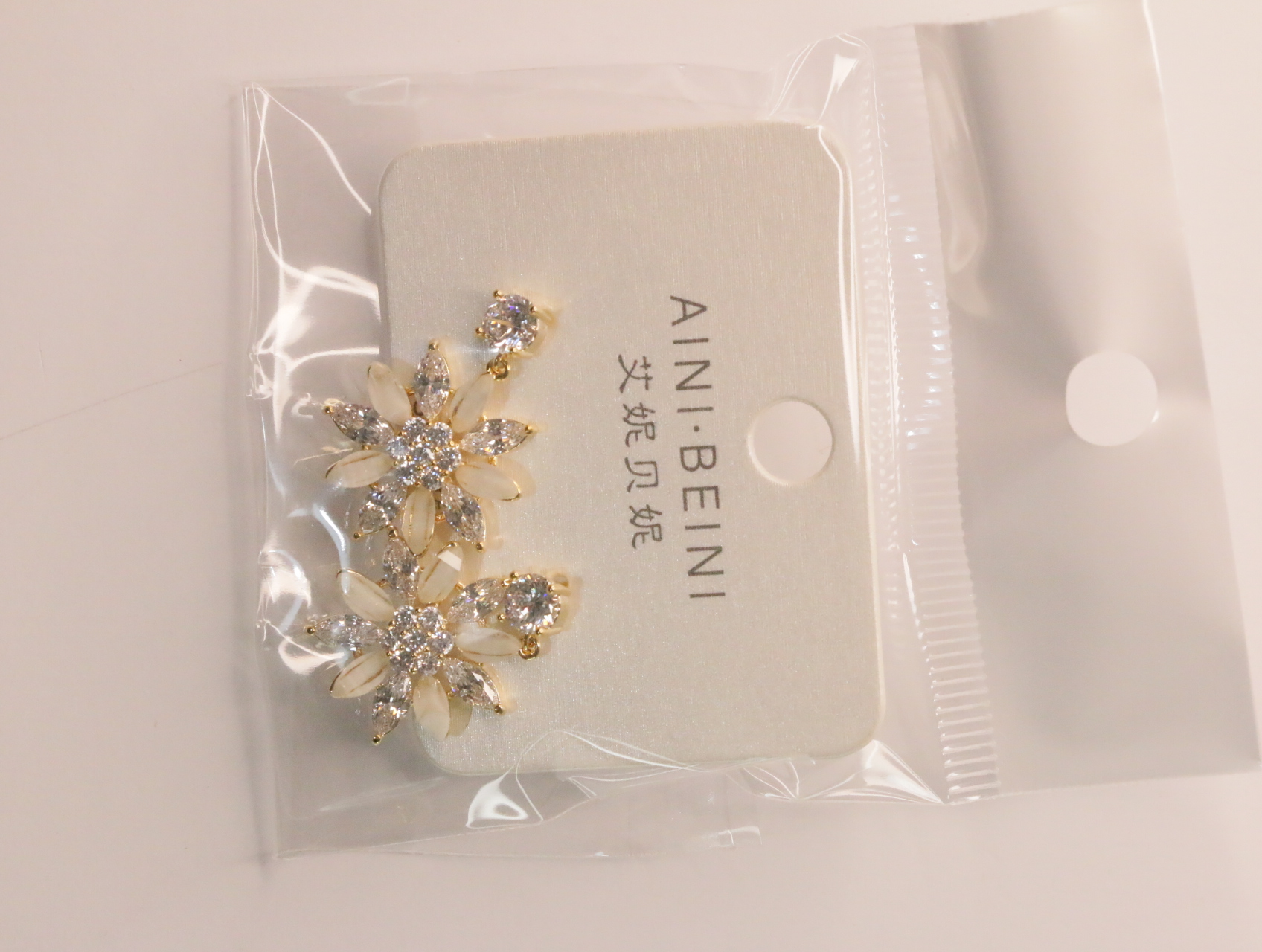 Detalle de pendientes florales dorados con adornos crema — lote de bisutería dorados, primer plano · Lotes Bisutería (LT060)