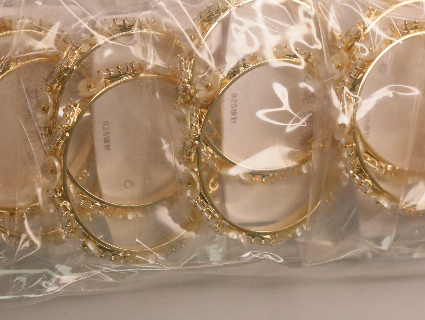 Detalle de aros dorados con adornos brillantes y efecto perla — lote de bisutería baratos, detalle · Lotes Bisutería (LT062)