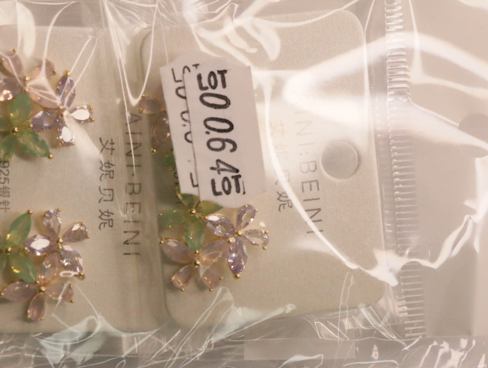 Pendientes florales en su envoltorio con etiqueta de referencia interna — lote de bisutería de moda, vista lateral · Lotes Bisutería (LT064)