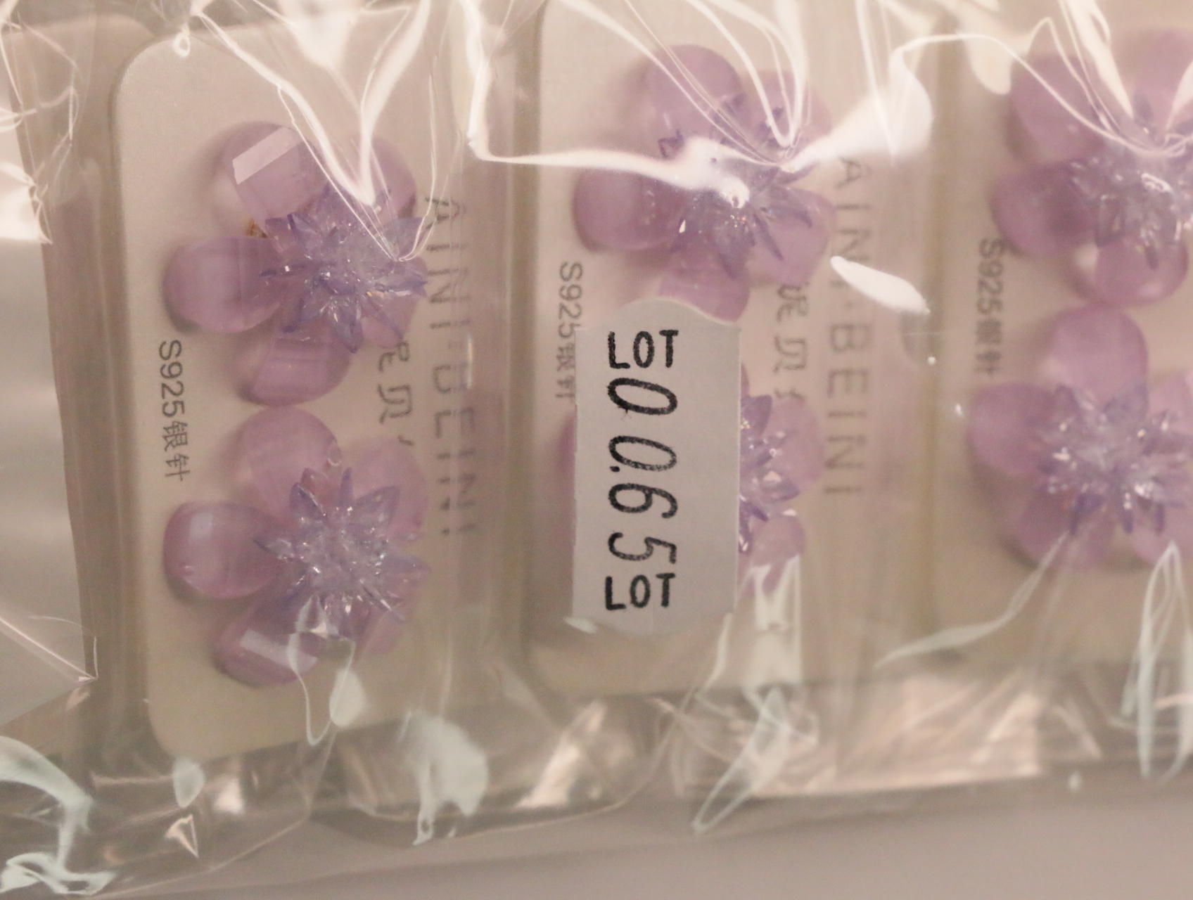 Pendientes de flor lila con etiqueta de referencia interna — lote de bisutería de moda, vista lateral · Lotes Bisutería (LT065)