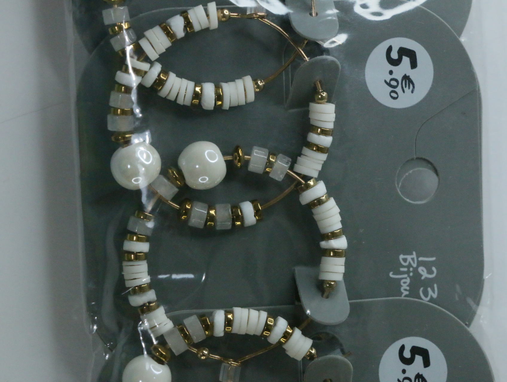 Detalle de cuentas blancas y translúcidas en los aros dorados — lote de bisutería de moda, vista lateral · Lotes Bisutería (LT068)
