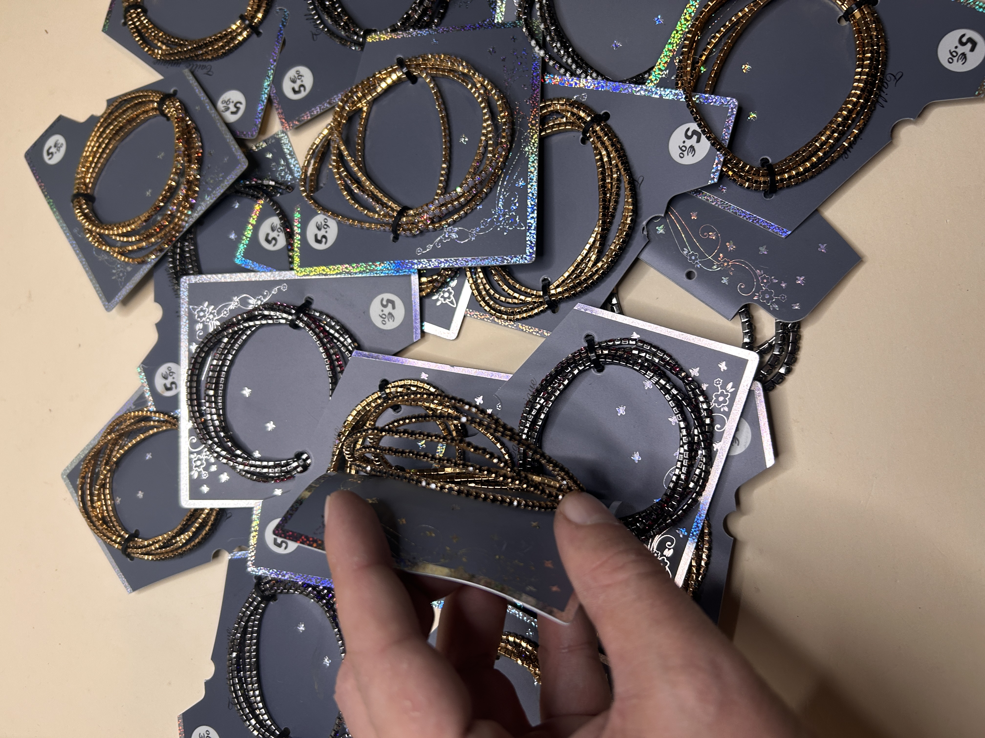 Mano sosteniendo una tarjeta con una pulsera de cuentas doradas y negras