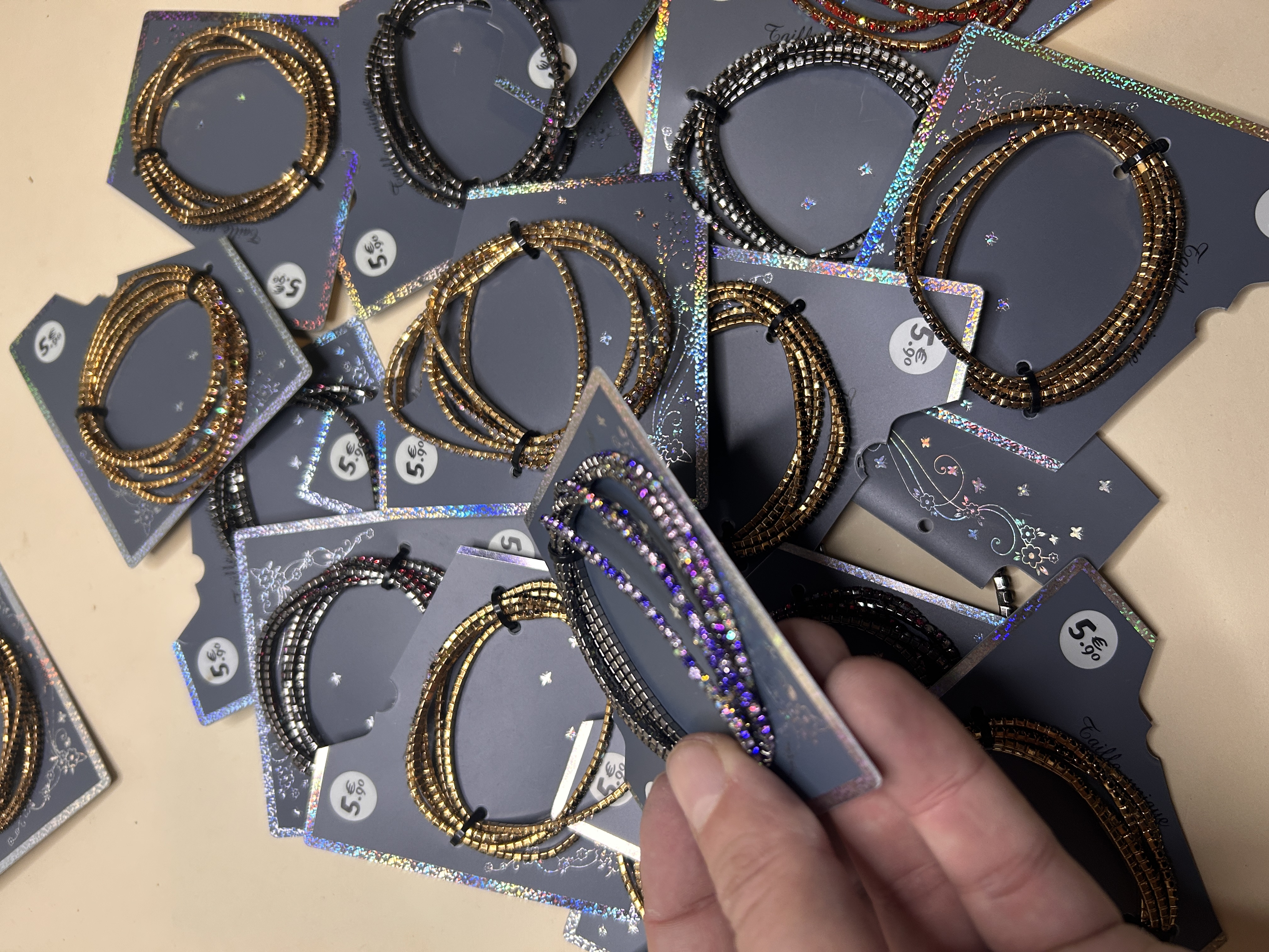 Primer plano de una mano sosteniendo una tarjeta con una pulsera de cuentas moradas y negras, mostrando detalle