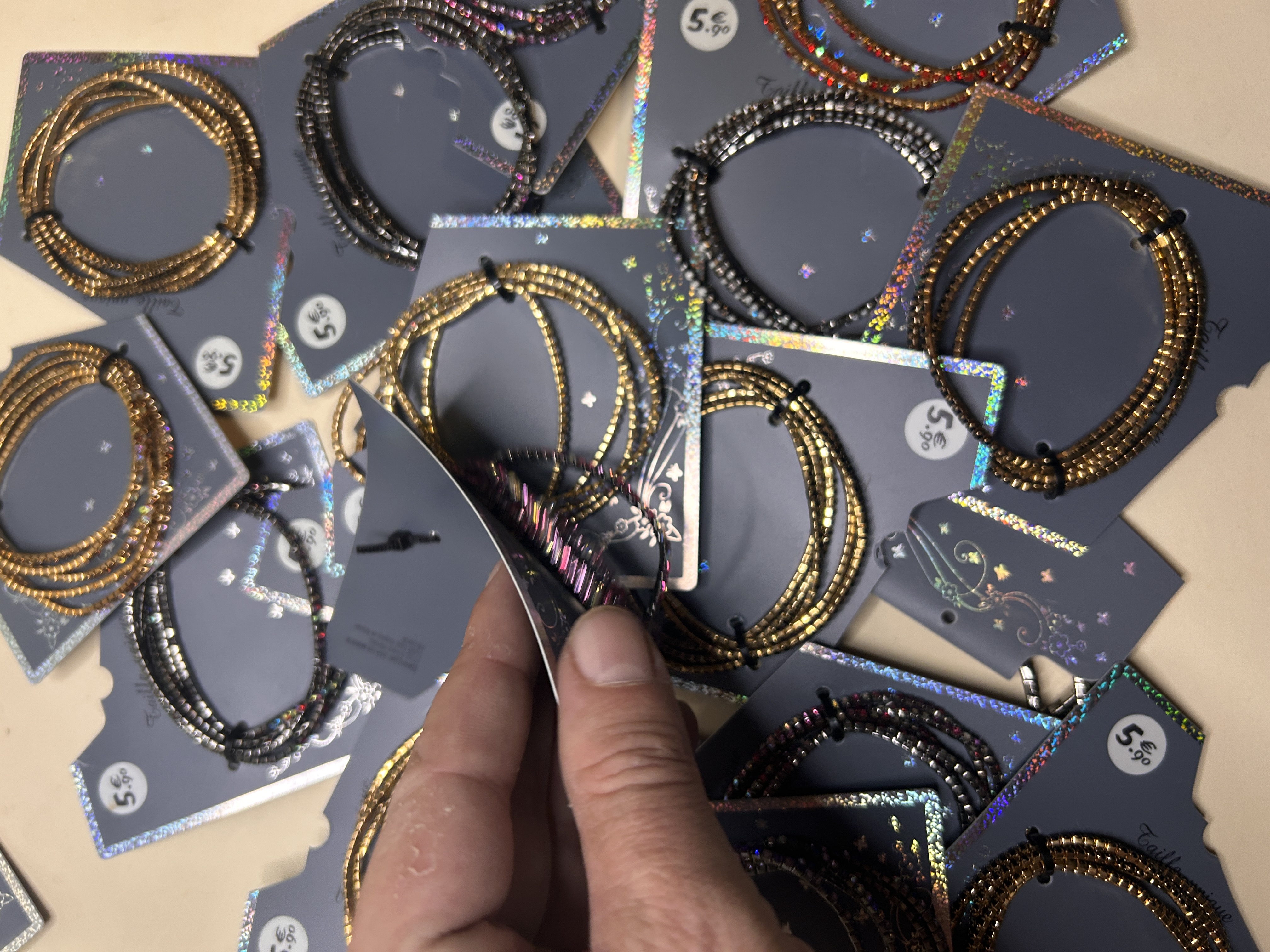 Mano abriendo una tarjeta para mostrar una pulsera de cuentas doradas